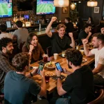 Fans engaging in sports betting at 888NEW, excitedly checking odds on smartphones